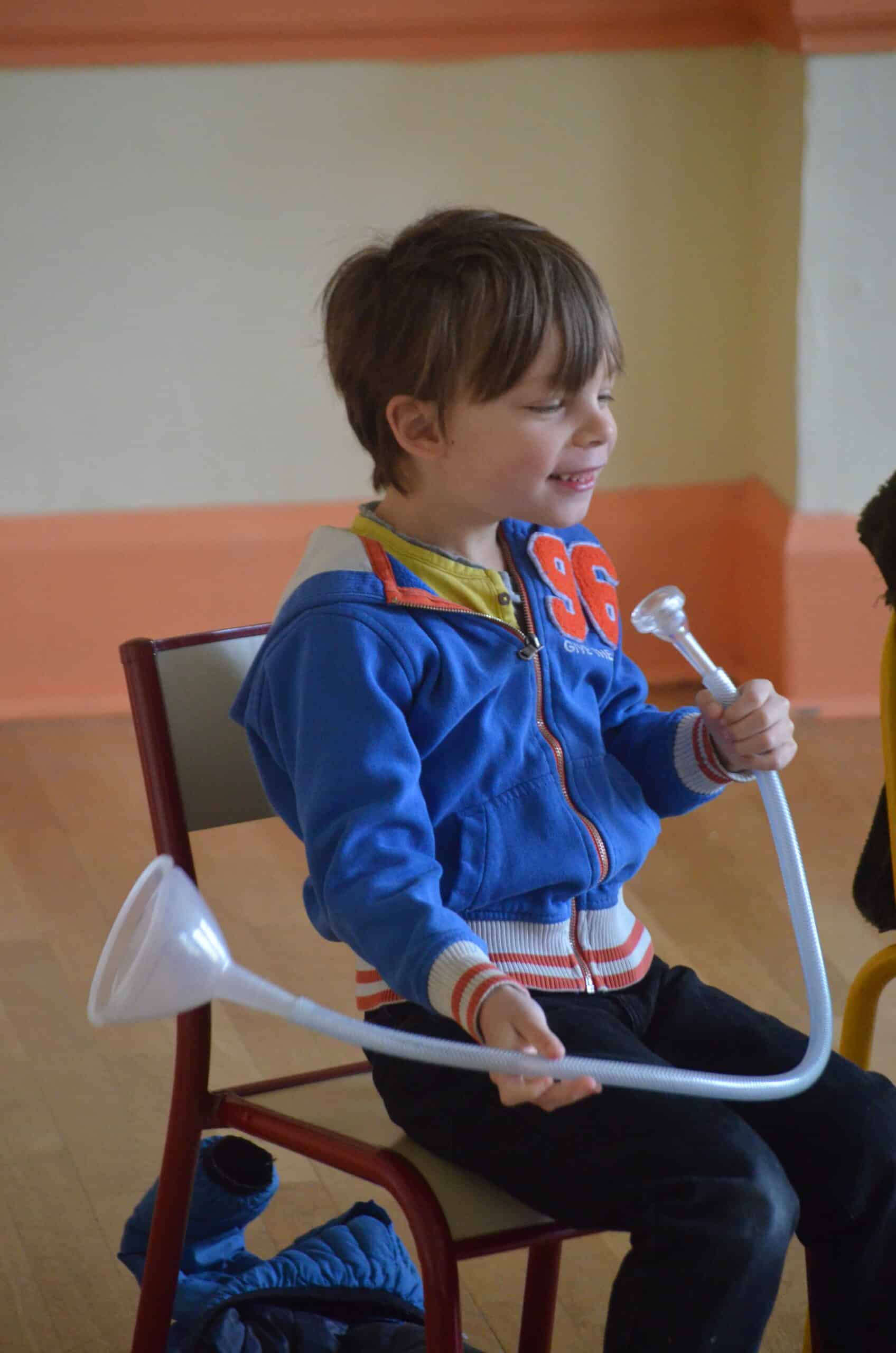 Un jeune garçon simule une trompette avec un entonnoir en plastique